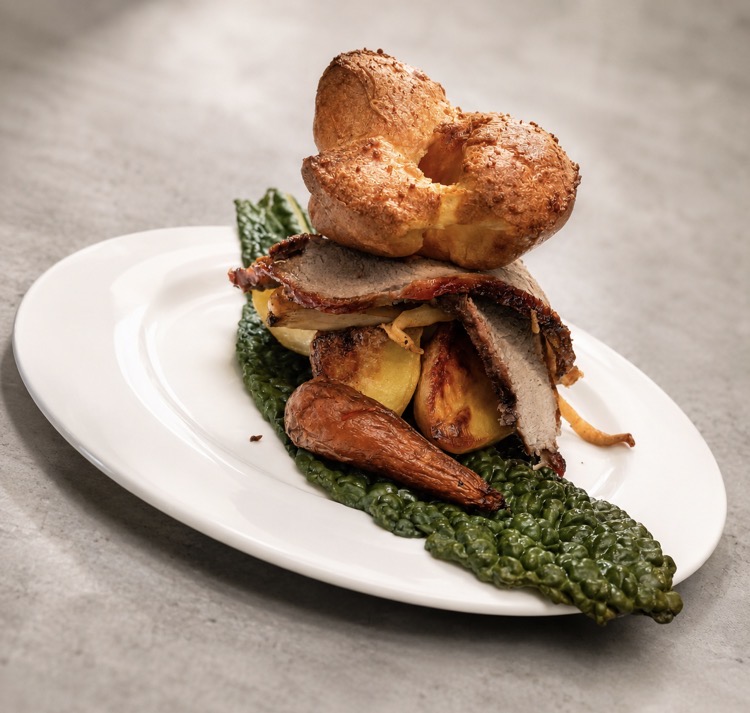 Plated roast beef with Yorkshire pudding, roast potatoes, carrot and kale