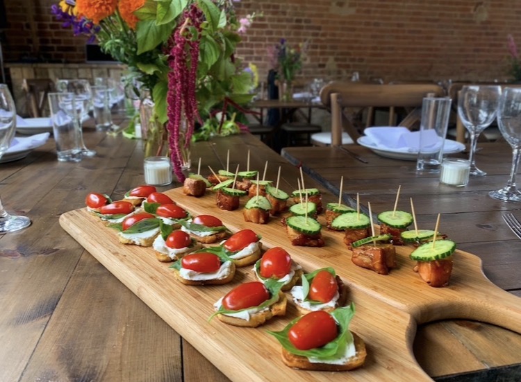 Wooden board of caprese and halloumi canapés on a dressed barn table