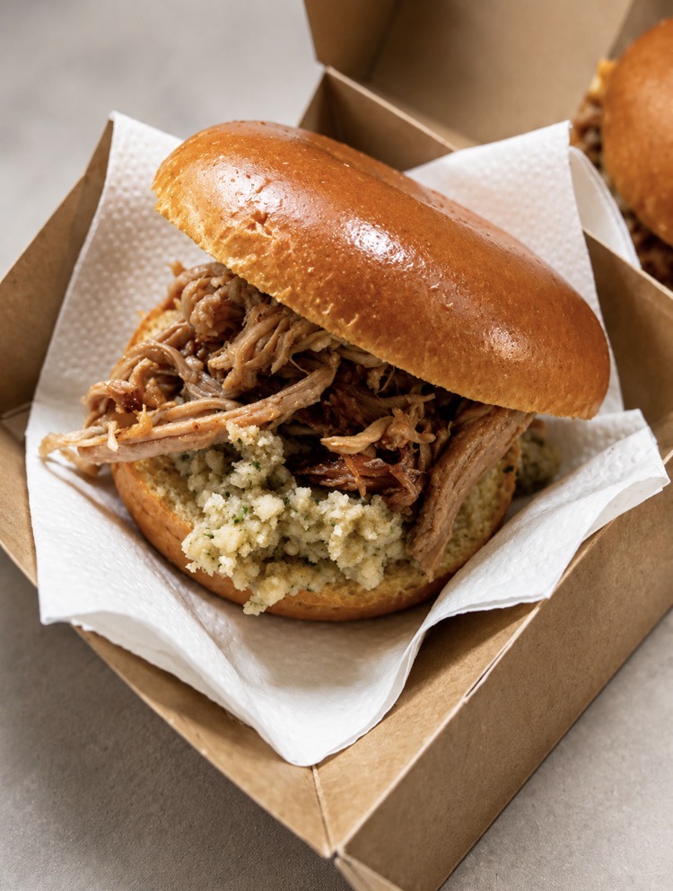 Slow-roasted hog roast roll with pulled pork, sage and onion stuffing and apple sauce in a brioche bun