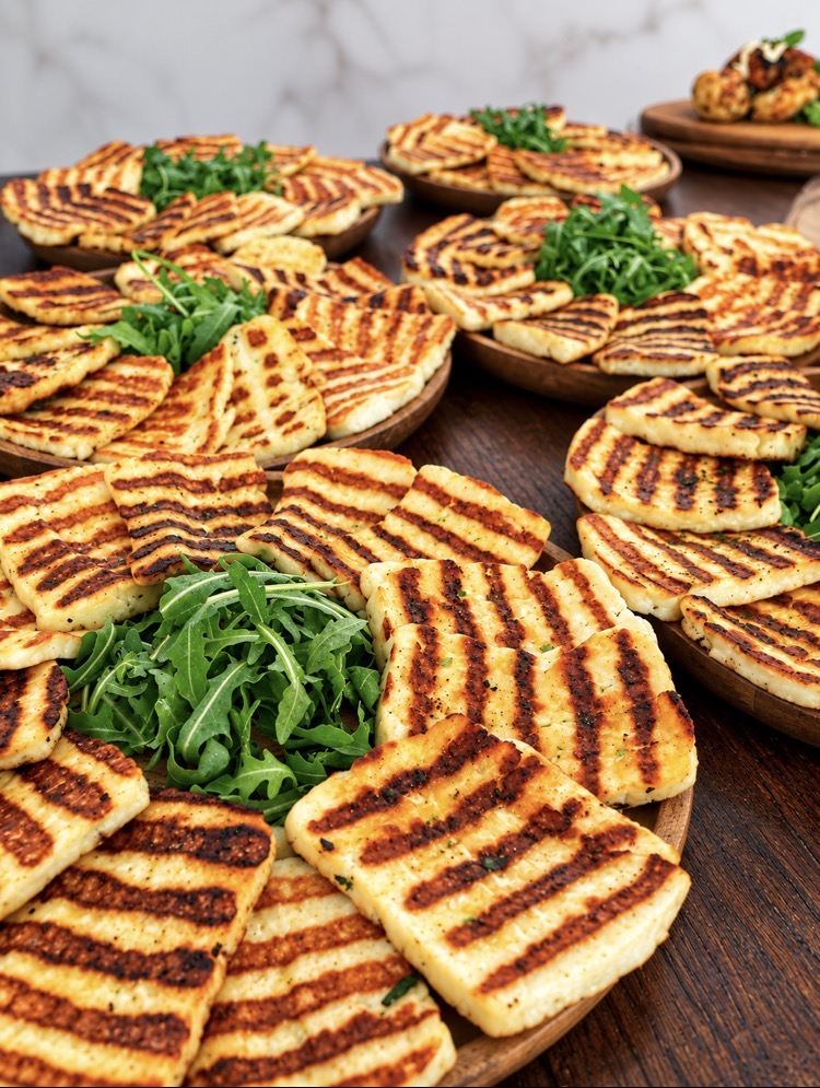 Wooden platters of grilled halloumi with fresh rocket ready for a sharing starter