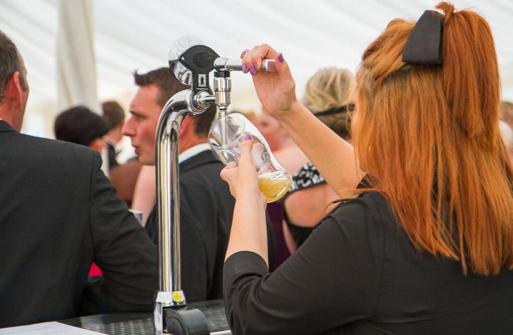 Server pouring a pint from a tap at a marquee drinks reception
