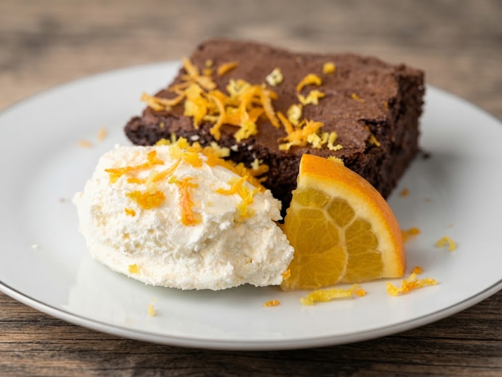 Chocolate brownie with orange zest, mascarpone cream and a fresh orange slice