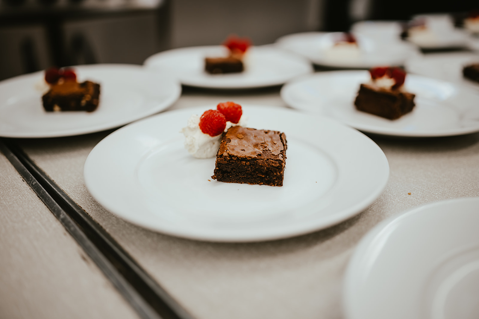 Chocolate brownies with cream and raspberries plated in a row