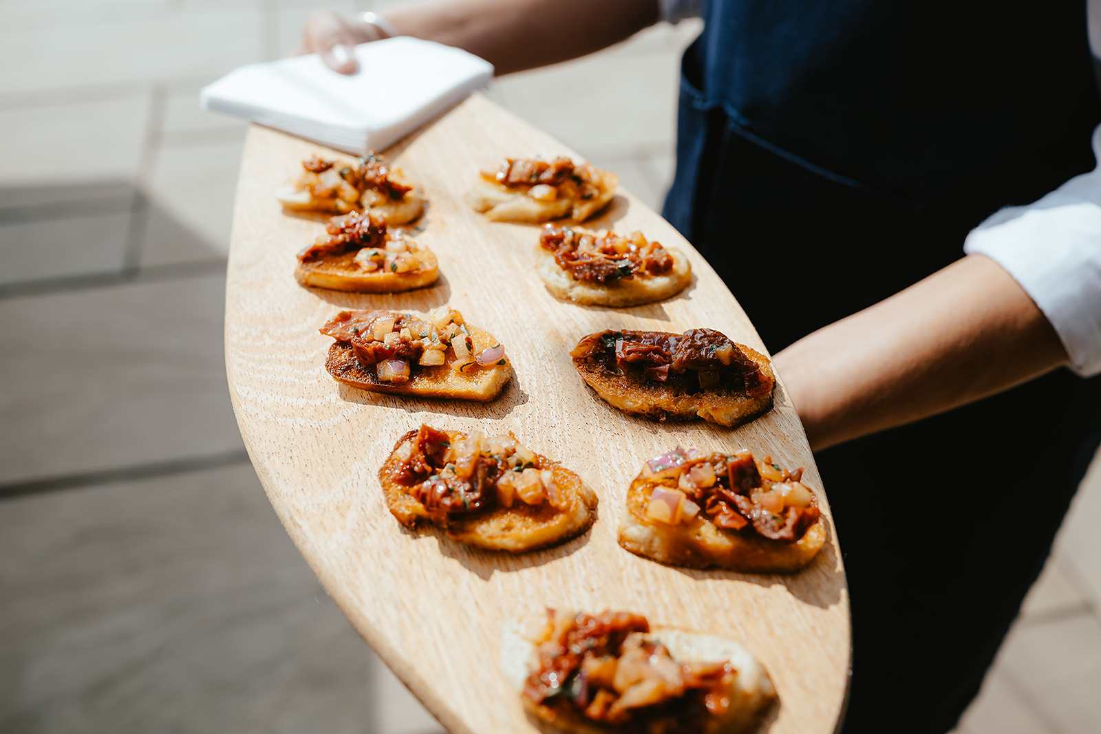 Server presenting a paddle of tomato bruschetta canapés at Godwick