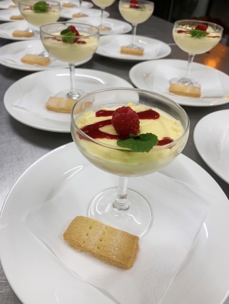 Lemon posset served in coupe glasses with raspberry, mint and shortbread