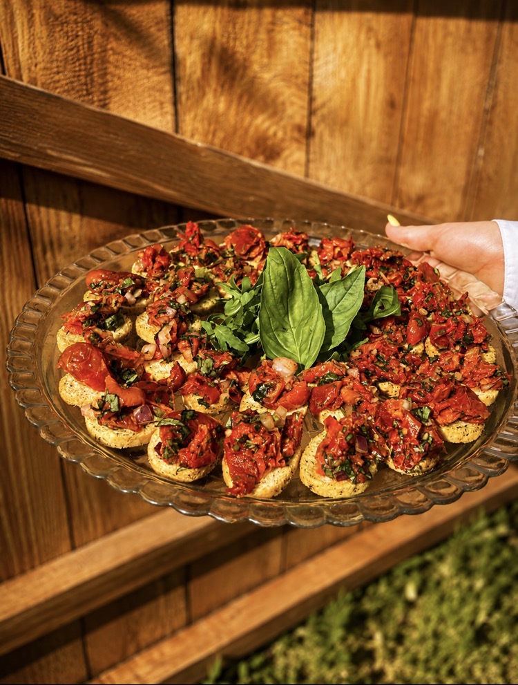 Glass platter of tomato and basil bruschetta canapés carried in the sunshine