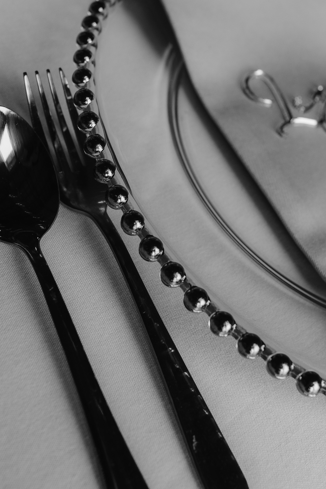 Black-and-white detail of polished cutlery and beaded charger plate at Hill Farm Barns
