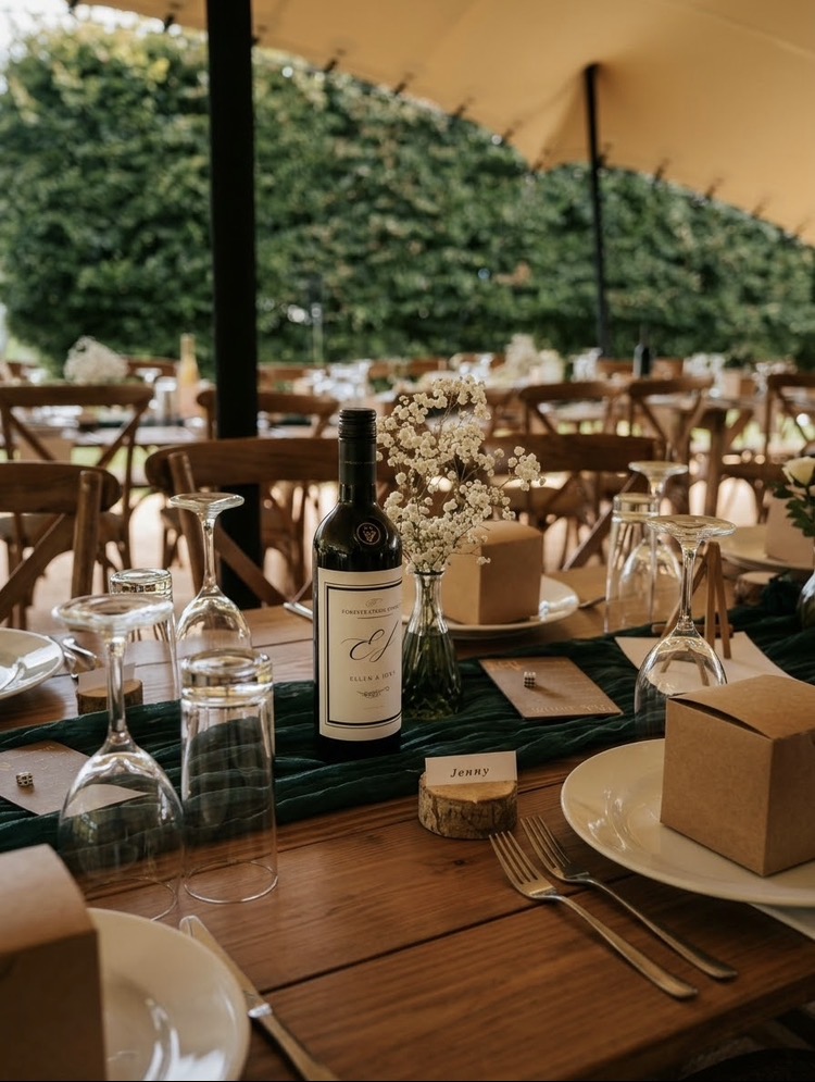 Wedding table under a sailcloth tipi with red wine, gypsophila, green runner and polished glassware