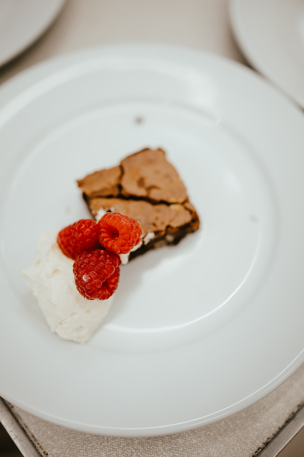 Close-up of a chocolate brownie with fresh raspberries and cream