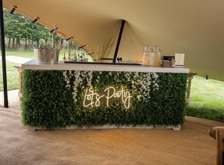 Rudd Catering mobile bar with a foliage front and Let's Party sign beneath a stretch tent