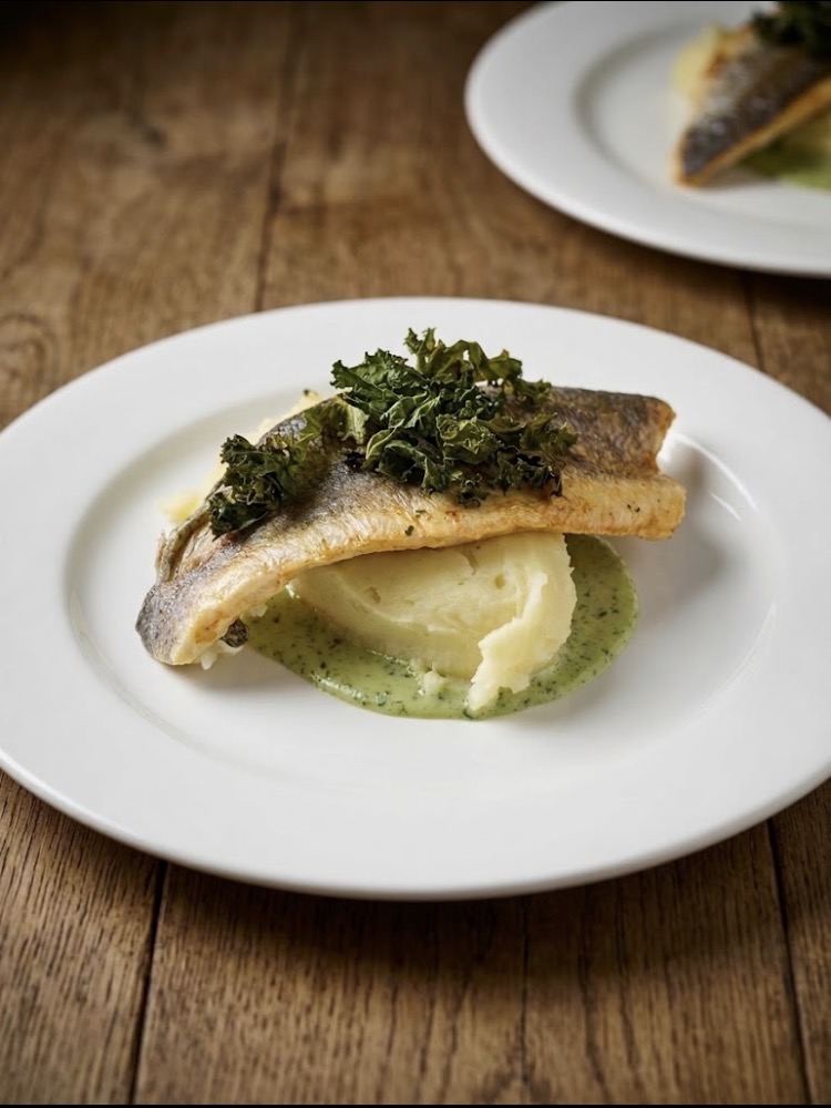 Pan-fried sea bass fillet with crispy kale, mash and herb butter sauce