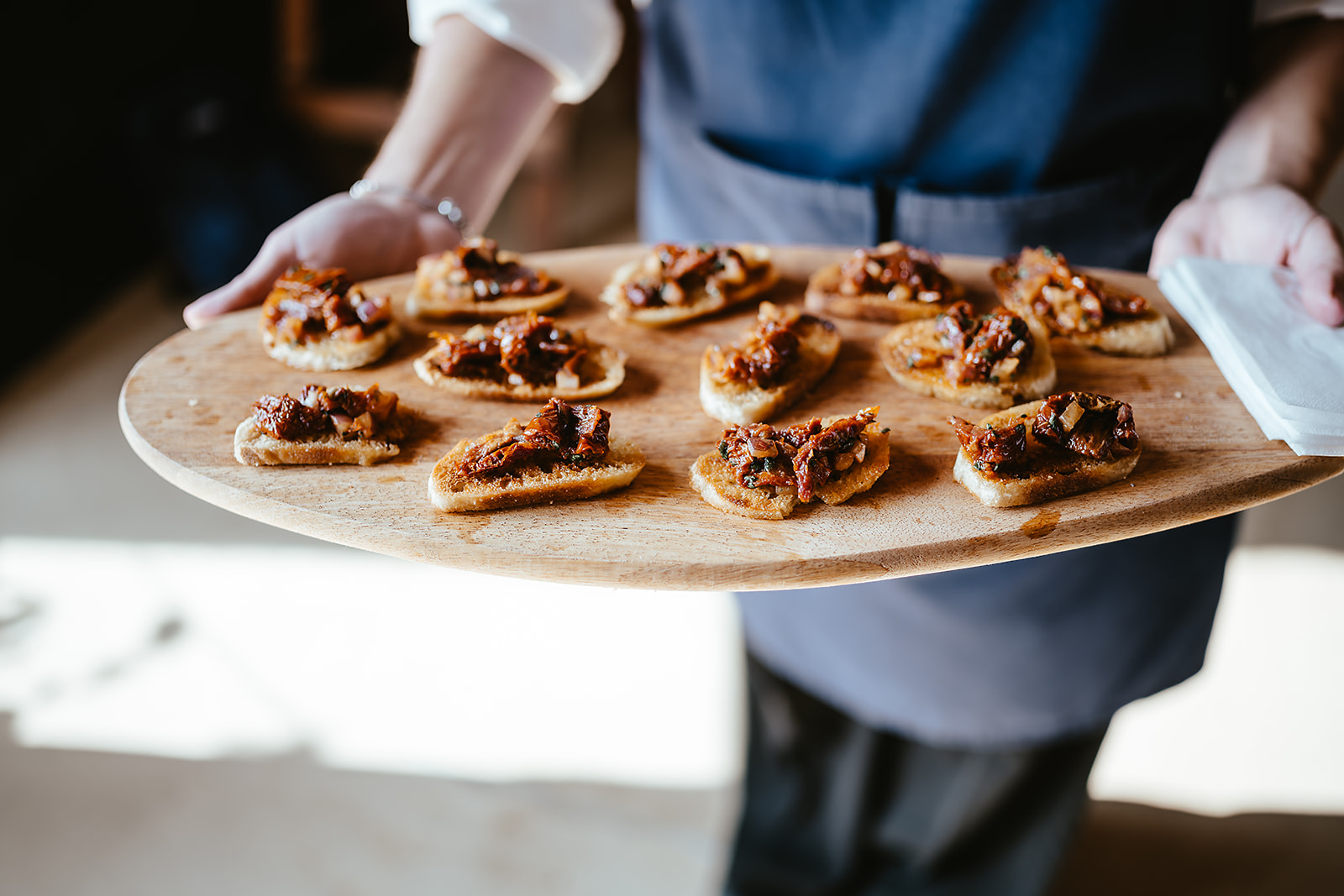Warm tomato and red onion bruschetta canapés on a large paddle