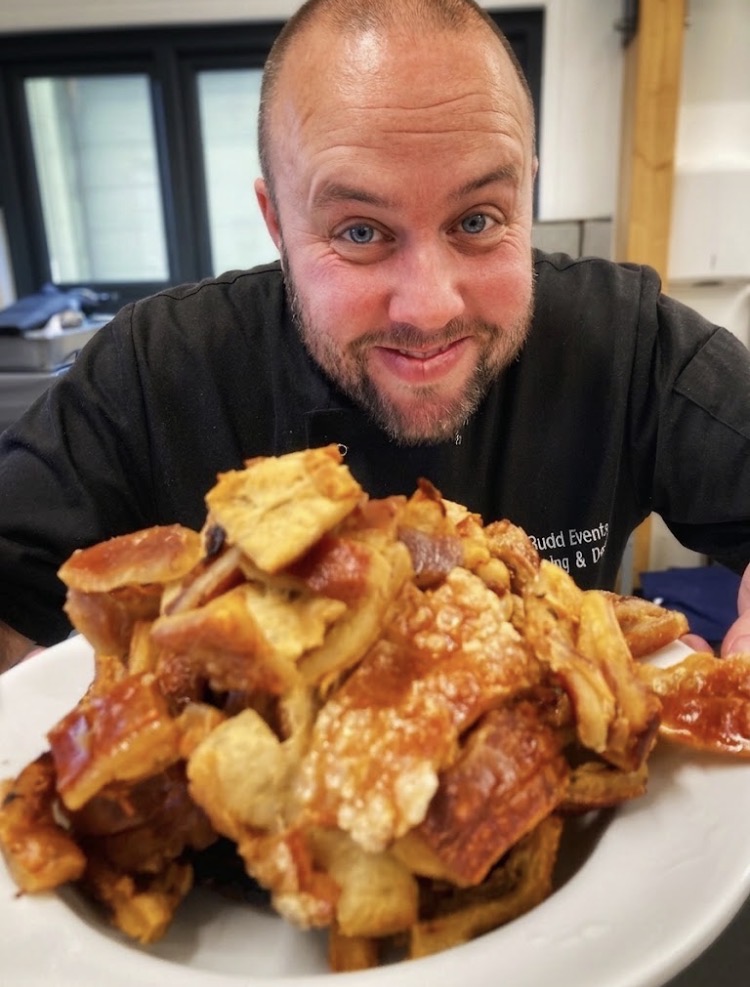 Chef holding a large bowl of golden pork crackling fresh from the oven
