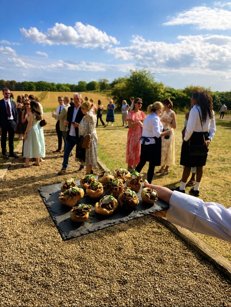 Slate of Yorkshire pudding canapés carried to guests at an outdoor drinks reception