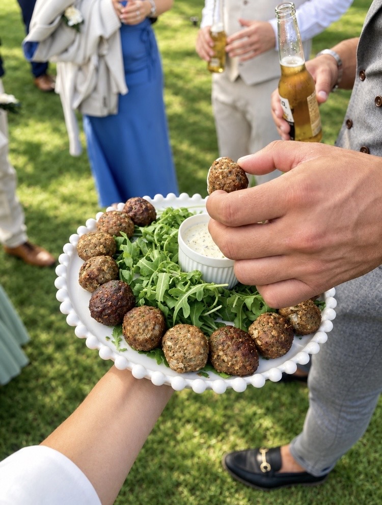 Falafel canapés with herb yoghurt dip handed round guests at an outdoor wedding reception
