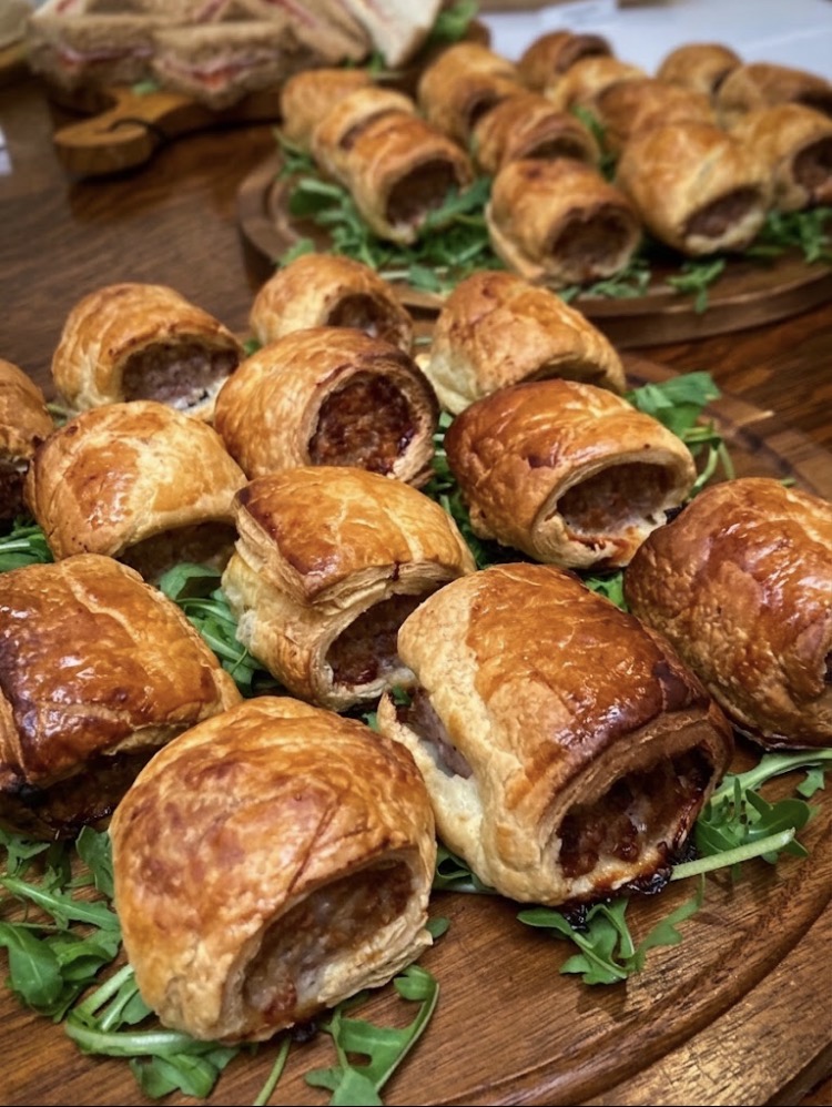 Warm butcher's sausage rolls on wooden boards with rocket