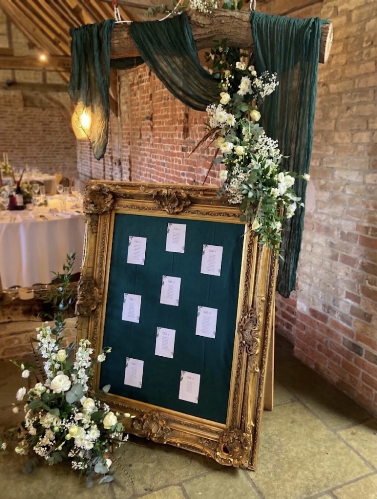 Ornate gold-framed wedding table plan at a barn venue