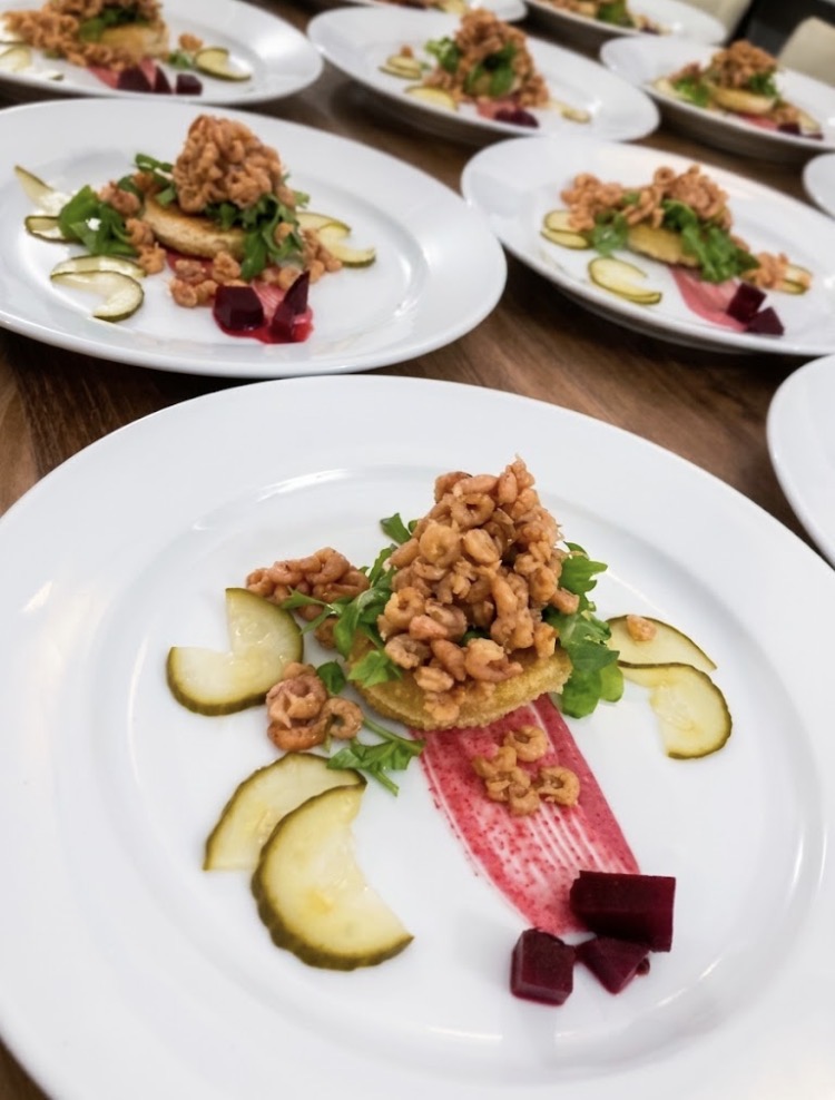 A line of crisp fried shrimp starters with pickled cucumber, beetroot and herb salad