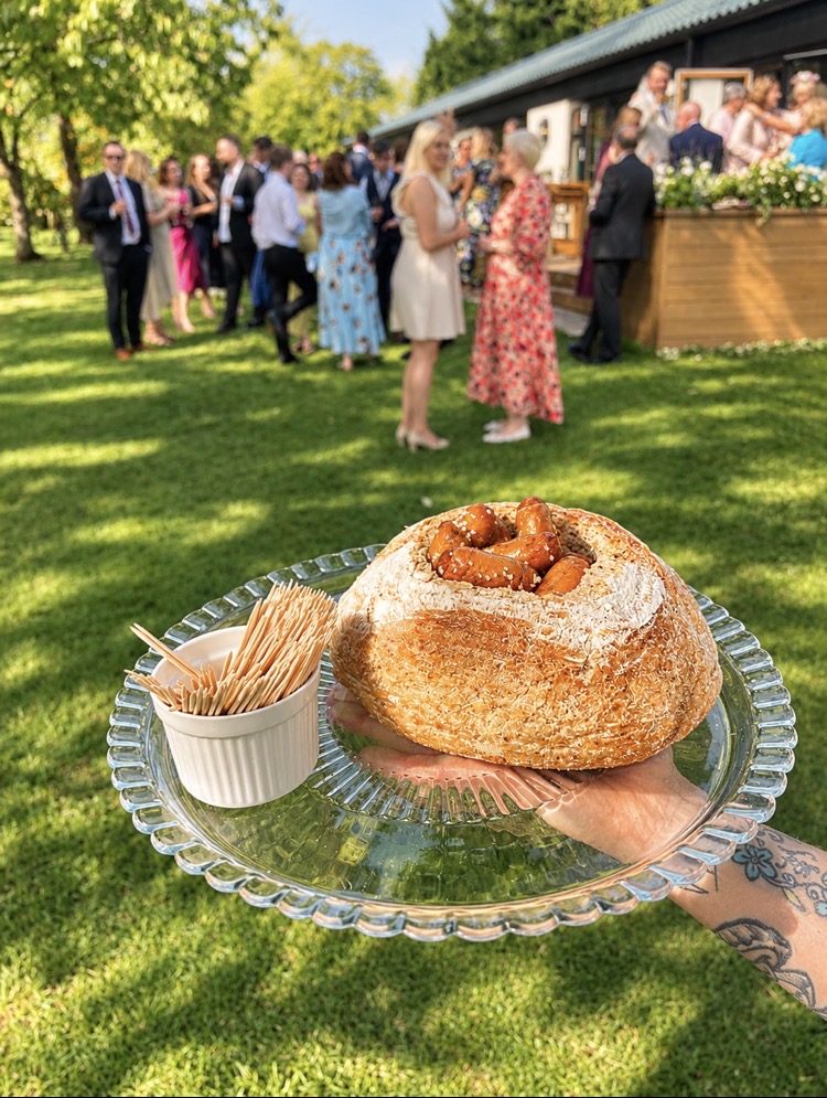 Rustic bread bowl filled with sausages served on a garden lawn