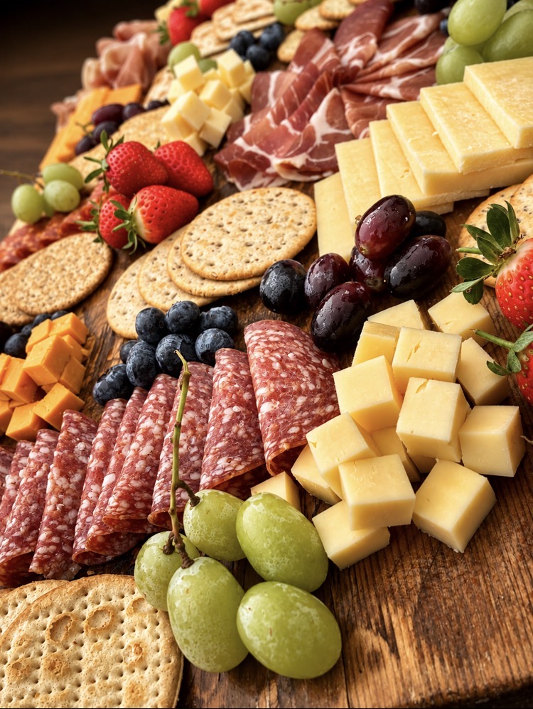 Close-up of a charcuterie and cheese board with grapes, berries and crackers