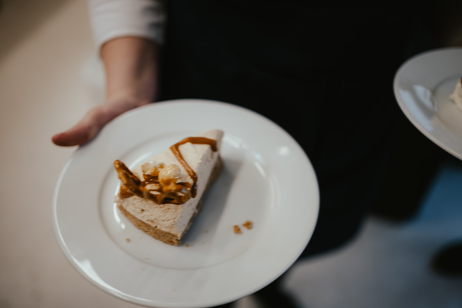 Server carrying a slice of salted caramel cheesecake